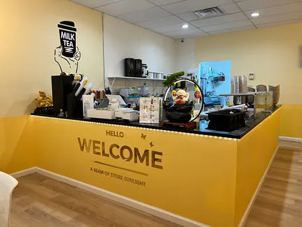 Bright yellow store counter with "WELCOME" sign and bubble tea decor at Asahi Poke & Tea, a Bubble tea store in Beacon