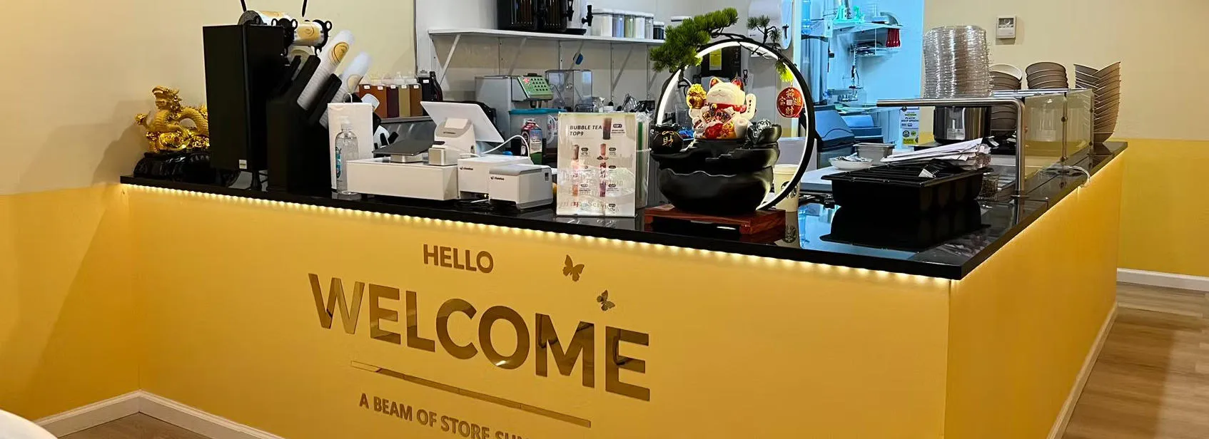 Bright yellow bubble tea store counter with POS system and decor at Asahi Poke & Tea, a Bubble tea store in Beacon