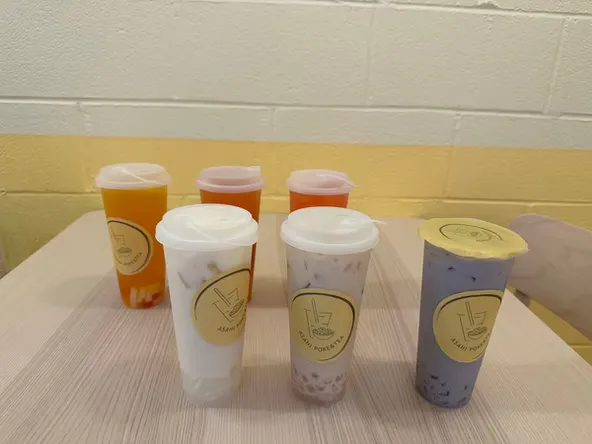 Six assorted bubble tea drinks in branded cups arranged on a table at Asahi Poke & Tea, a Bubble tea store in Beacon
